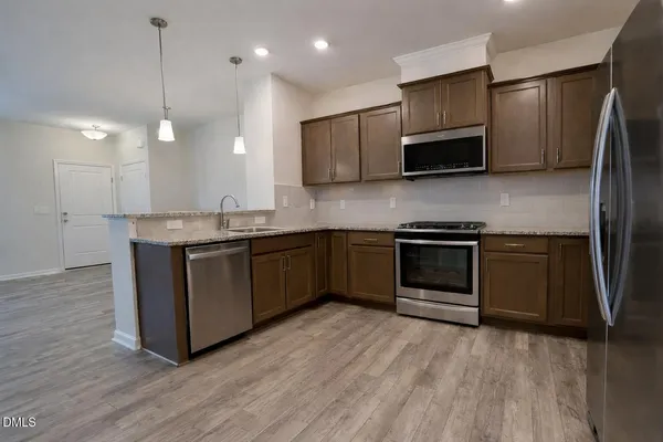 a kitchen with stainless steel appliances granite countertop a stove a sink and a microwave
