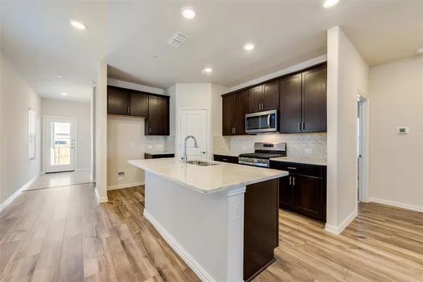 a large kitchen with stainless steel appliances a large counter top a stove and a sink