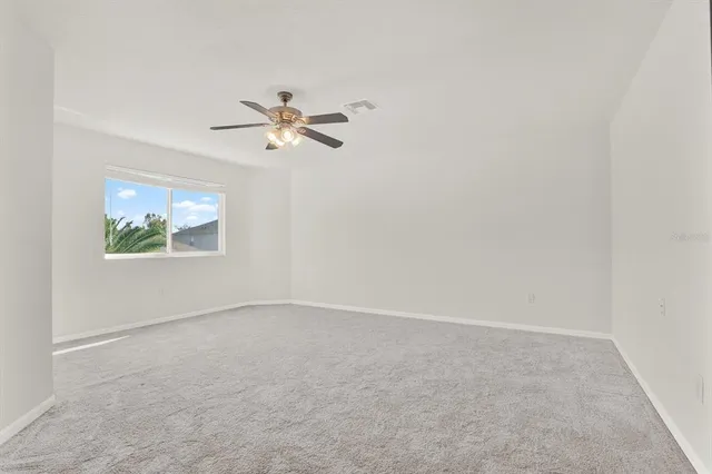 an empty room with a window and a ceiling fan