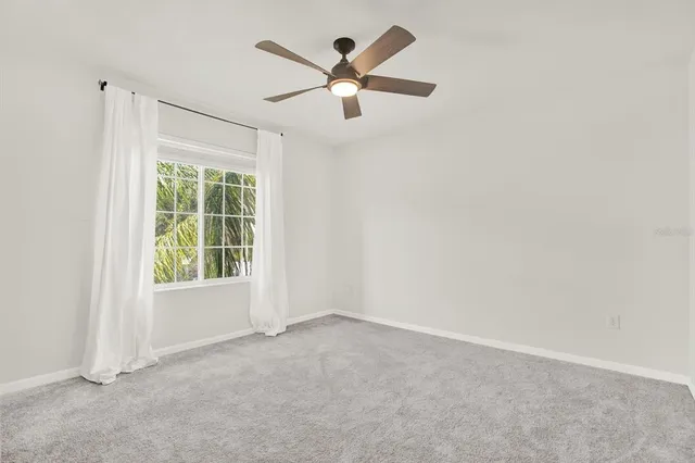 an empty room with ceiling fan and windows