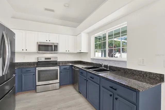 a kitchen with granite countertop a sink and steel appliances