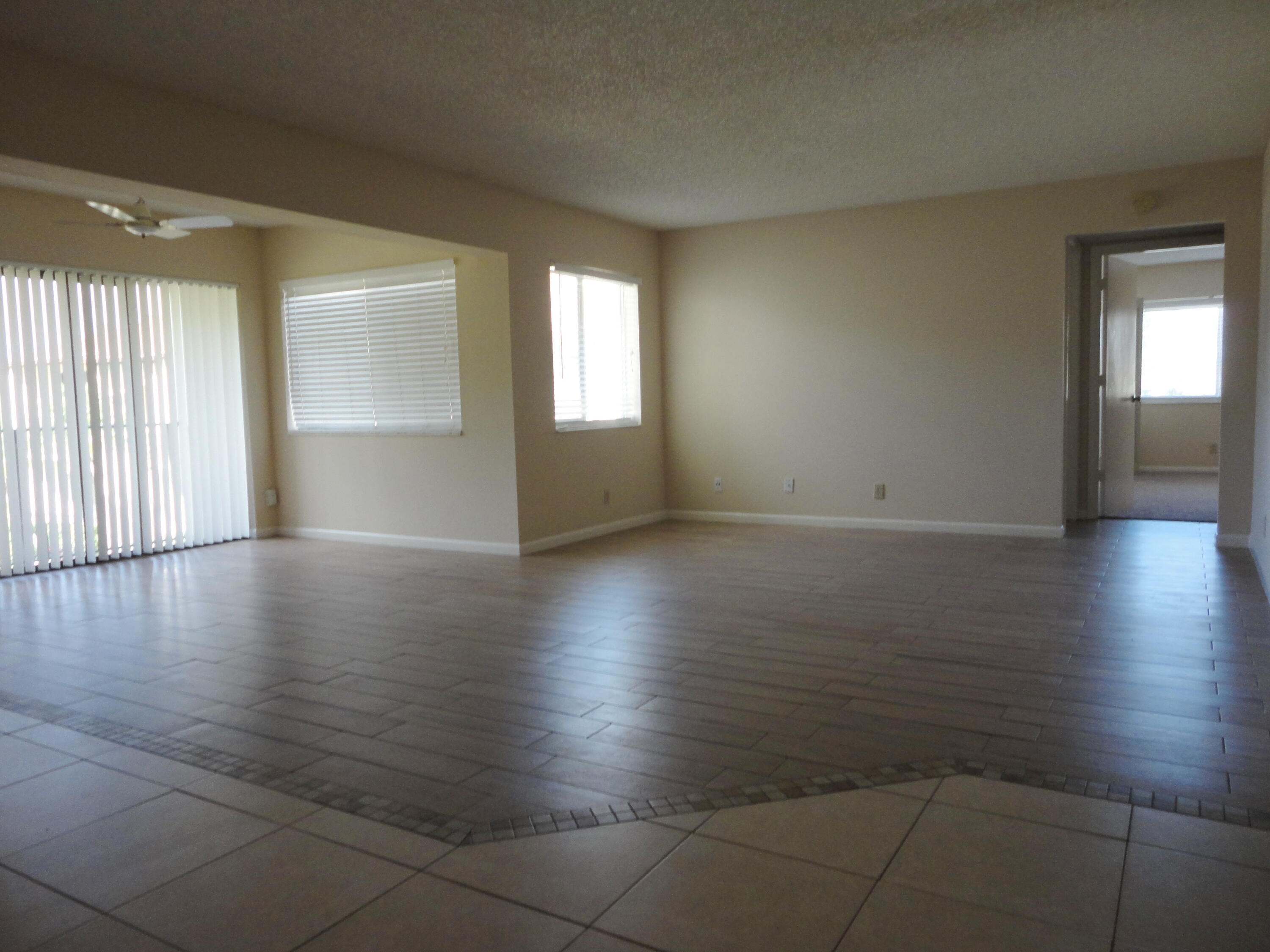 4695 Sable Pine Circle, Unit C2 West Palm Beach, FL 33417 - Photo 2 of 14 an empty room with wooden floor and windows with curtains