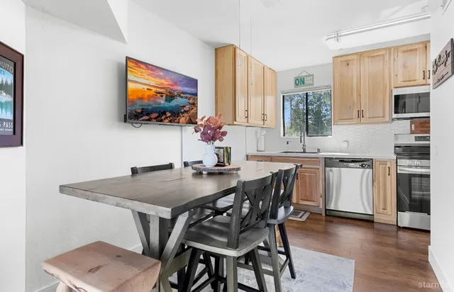 a kitchen with a table chairs a flat screen tv and a stove