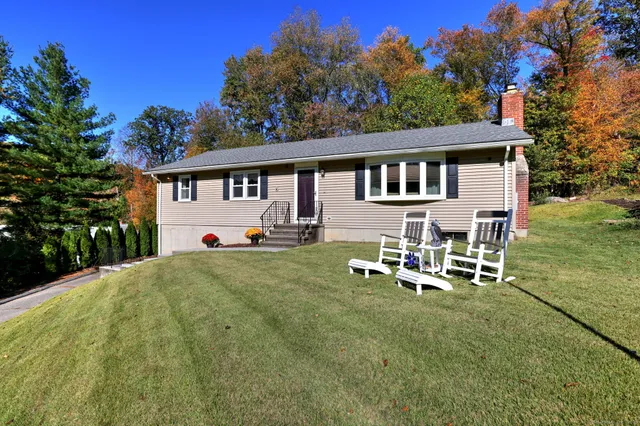 a front view of a house with a garden and chairs
