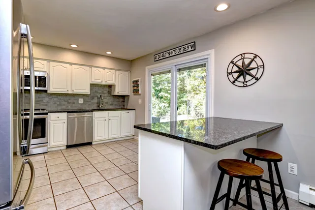 a kitchen with stainless steel appliances granite countertop a stove a sink and a microwave