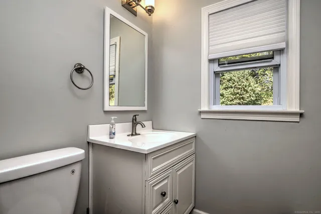 a bathroom with a granite countertop toilet a sink and a mirror