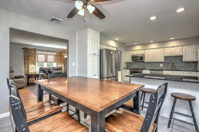 a kitchen with stainless steel appliances kitchen island granite countertop a dining table chairs and refrigerator