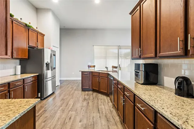 a kitchen with granite countertop a refrigerator stove and microwave