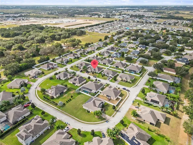 a view of a white house next to a yard with large trees