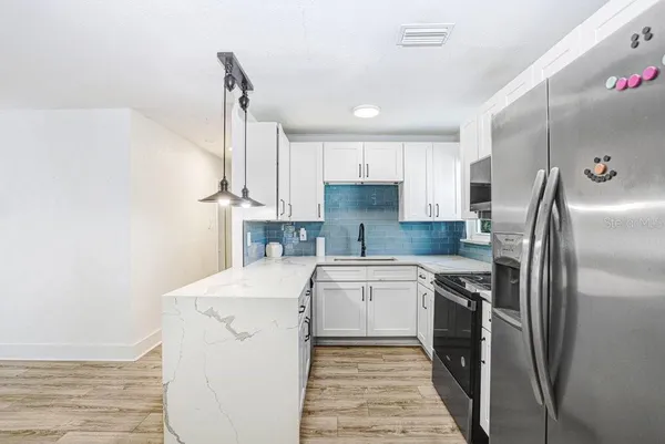 a kitchen with a sink a refrigerator and white cabinets