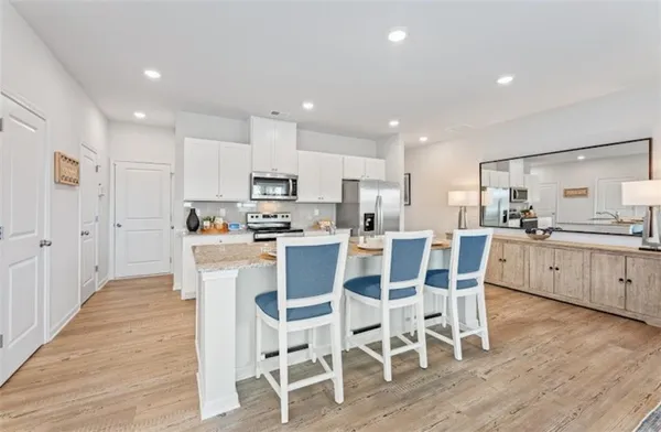a kitchen with a dining table chairs wooden floor cabinets and stainless steel appliances