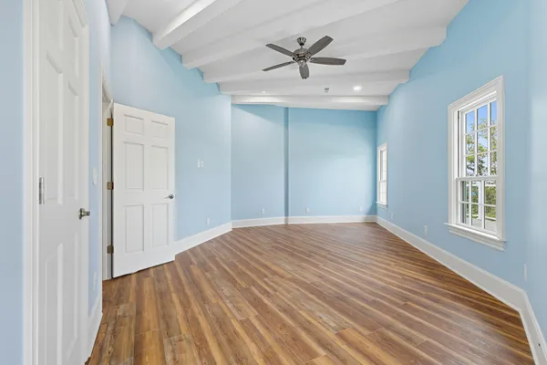 an empty room with wooden floor cabinet and windows