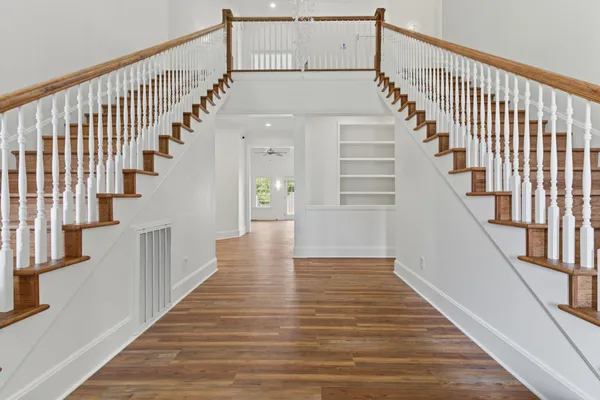 a view of staircase with lots of frames on wall and wooden floor