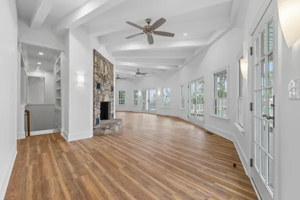 a view of an empty room with wooden floor and a kitchen