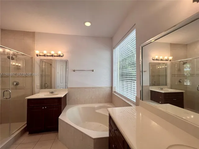 a bathroom with a bathtub a sink a mirror and a shower