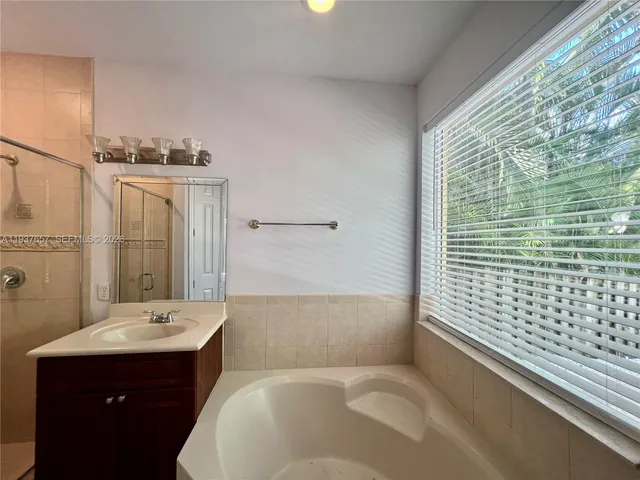 a bathroom with a bathtub sink vanity and mirror