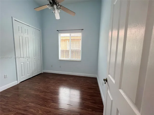 an empty room with wooden floor fan and windows