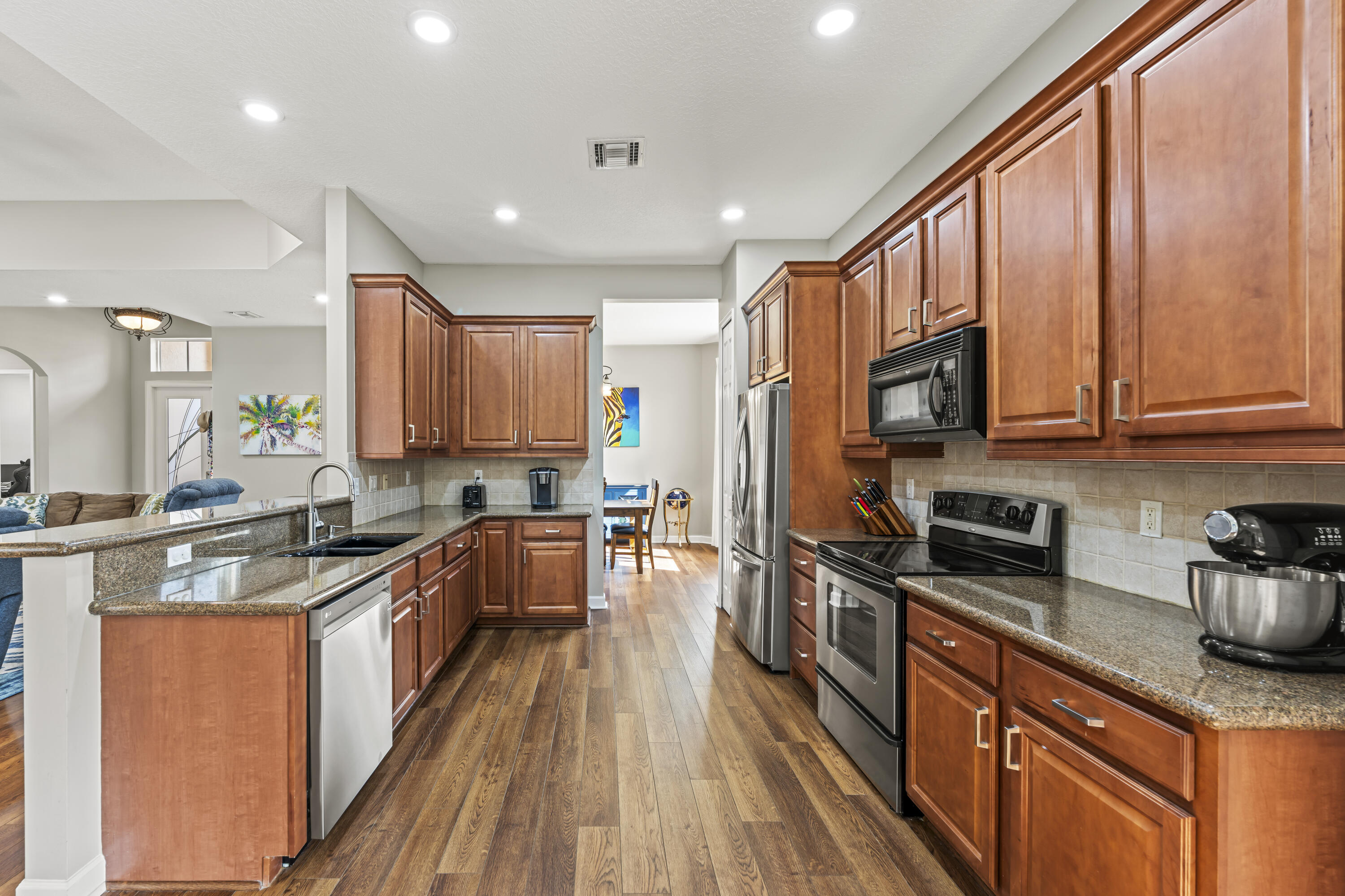 9184 Pumpkin Ridge Port St. Lucie, FL 34986 - Photo 15 of 74 a kitchen with stainless steel appliances granite countertop wooden cabinets a refrigerator a sink a stove and a wooden floors
