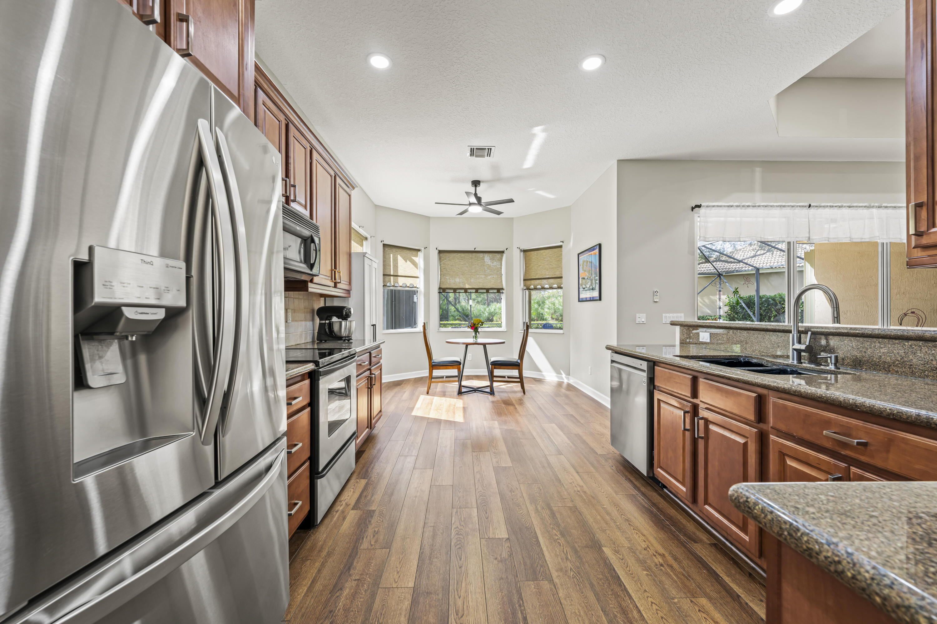 9184 Pumpkin Ridge Port St. Lucie, FL 34986 - Photo 18 of 74 a kitchen with stainless steel appliances granite countertop a refrigerator a sink dishwasher a stove and white countertops with wooden floor