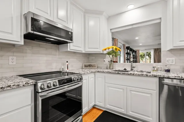 a kitchen with stainless steel appliances granite countertop a stove a sink and a microwave