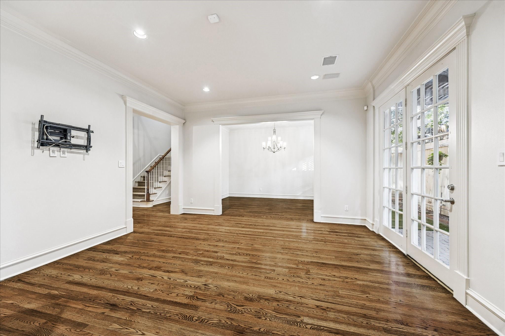 5823 Augusta Court Houston, TX 77057 - Photo 8 of 44 The family room is a spacious, bright living area with hardwood floors and neutral walls. French doors lead to a patio, and there's a mounted bracket for a TV.
