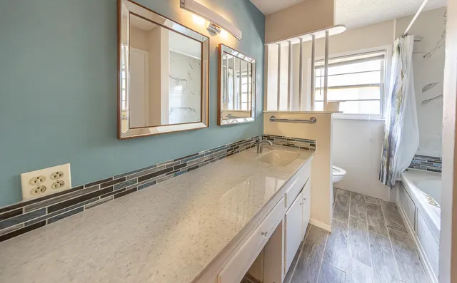 a bathroom with a granite countertop sink a large mirror and a toilet