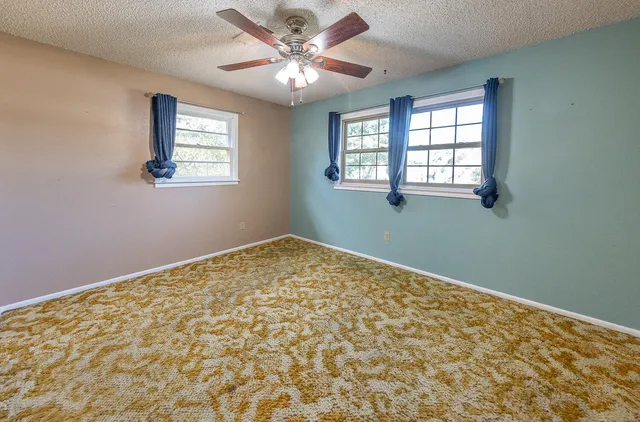 a view of a big room with windows and chandelier fan