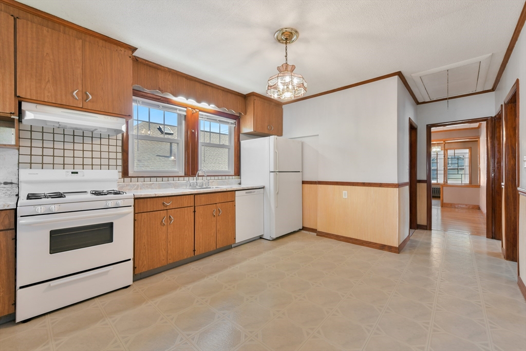 331-333 Vermont Street Boston, MA 02132 - Photo 15 of 26 a kitchen with granite countertop a refrigerator a sink dishwasher a stove and white cabinets with wooden floor