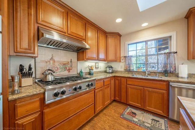 a kitchen with stainless steel appliances granite countertop a stove a sink and cabinets