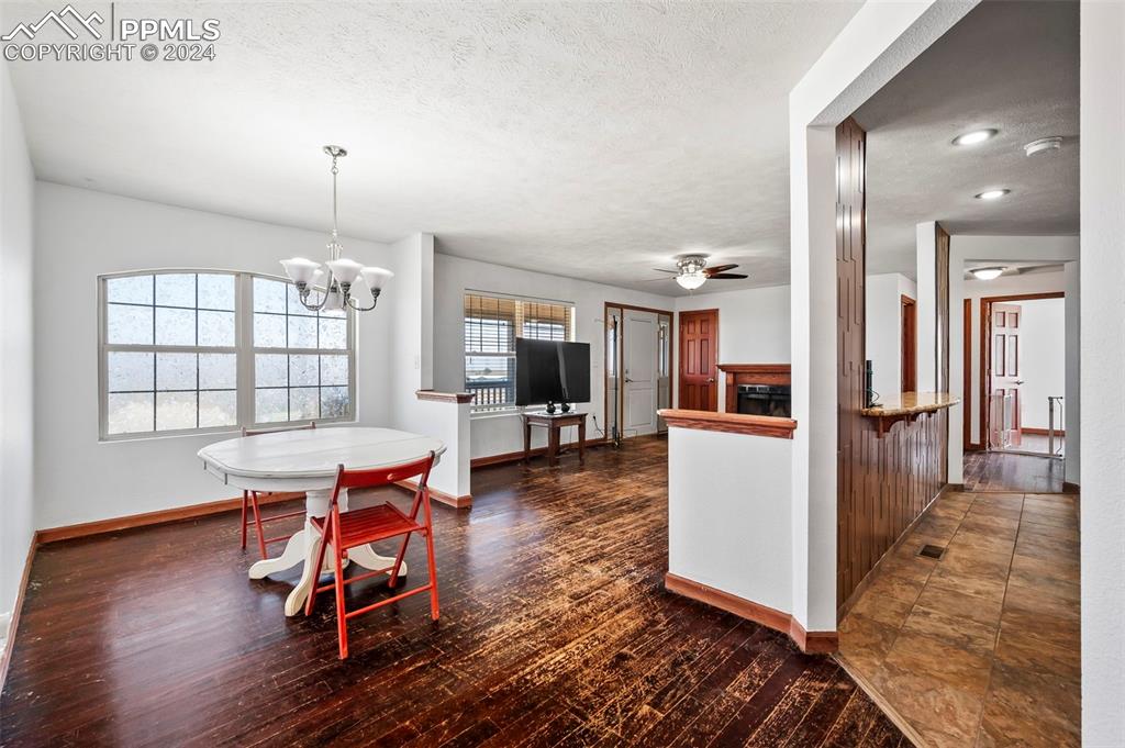 6260 Night Train Lane Yoder, CO 80864 - Photo 12 of 22 Kitchen featuring dark tile floors, ceiling fan with notable chandelier, a textured ceiling, and pendant lighting