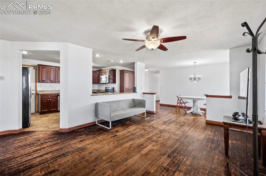 6260 Night Train Lane Yoder, CO 80864 - Photo 9 of 22 Living room with wood-type flooring and ceiling fan with notable chandelier
