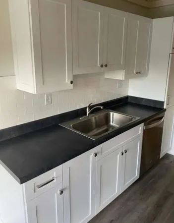 a kitchen with granite countertop white cabinets and sink