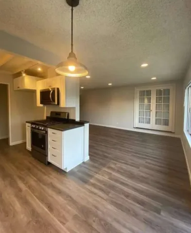 a kitchen with granite countertop a stove and a wooden floor