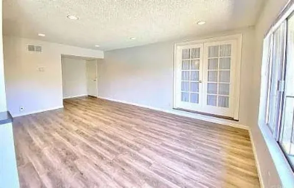 an empty room with wooden floor and windows