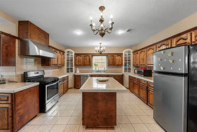 a kitchen with stainless steel appliances granite countertop a stove top oven a sink dishwasher and a refrigerator