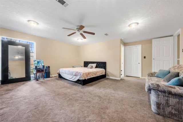 a spacious bedroom with a bed and a ceiling fan