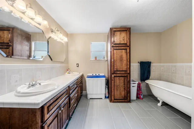 a bathroom with a double vanity sink mirror and bathtub