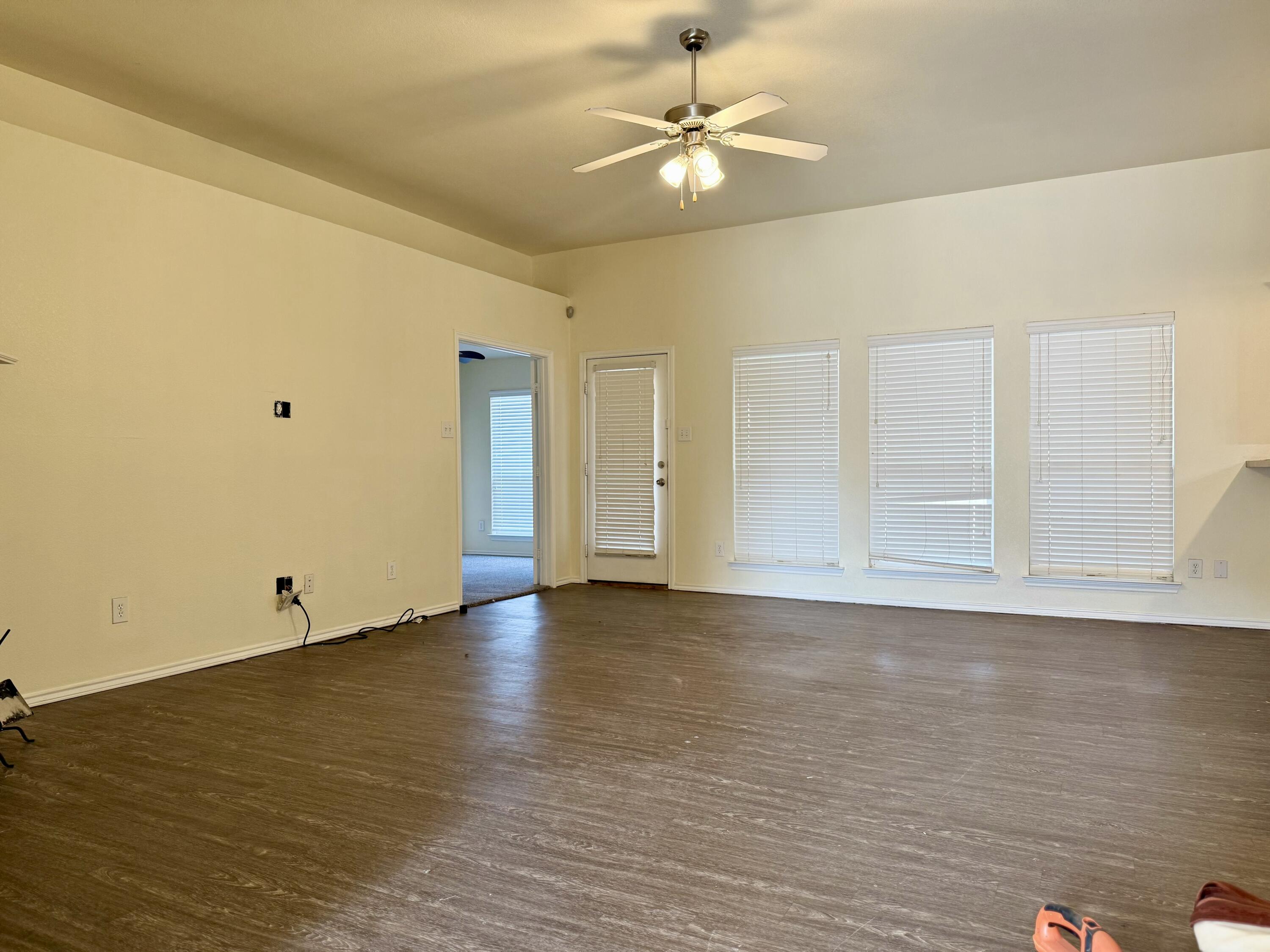 4916 Harvard Drive Lubbock, TX 79416 - Photo 4 of 22 an empty room with wooden floor fan and windows
