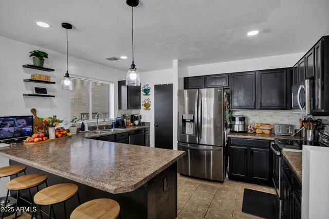 a kitchen with stainless steel appliances granite countertop a sink a stove and refrigerator