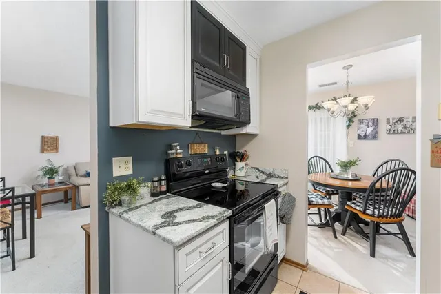 a kitchen with granite countertop a stove a sink and a dining table with chairs