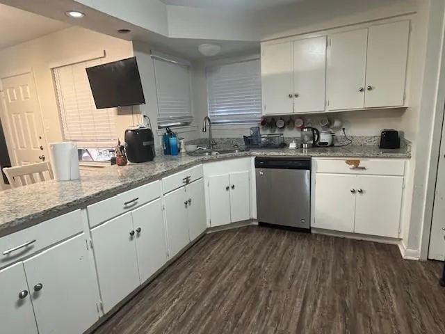 a kitchen with granite countertop cabinets stainless steel appliances a sink and wooden floor