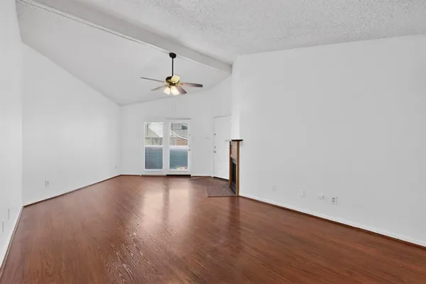 an empty room with wooden floor chandelier fan and windows