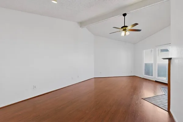 a view of an empty room with a window and wooden floor