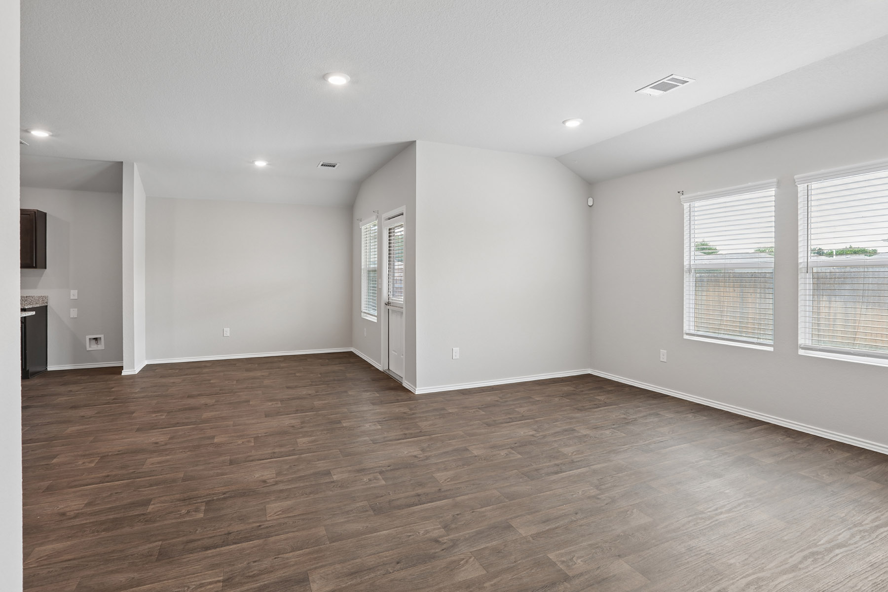 15217 Upland Willow Road Austin, TX 78724 - Photo 18 of 25 Unfurnished living room featuring dark wood finished floors, lofted ceiling, and recessed lighting