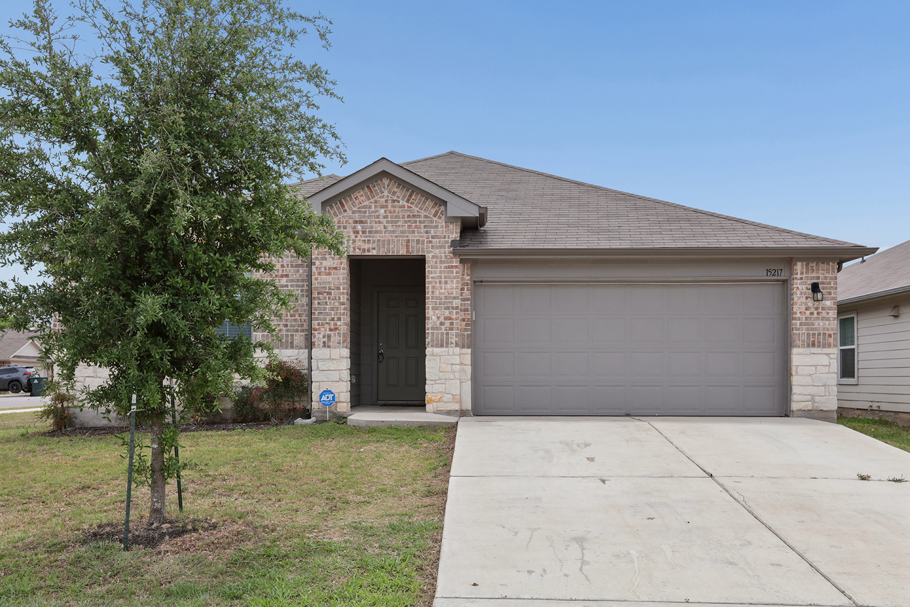 15217 Upland Willow Road Austin, TX 78724 - Photo 3 of 25 Front featuring a shingled roof, driveway, an attached garage, brick siding, and a front lawn