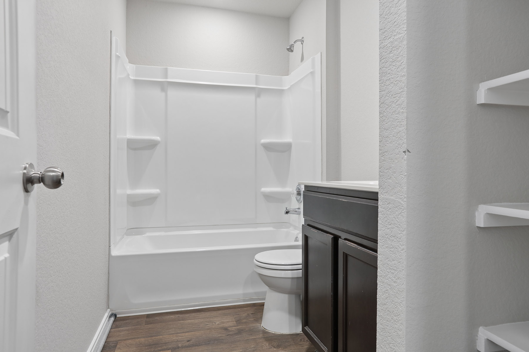15217 Upland Willow Road Austin, TX 78724 - Photo 7 of 25 Full bathroom featuring a textured wall, dark wood-type flooring, vanity, and tub / shower combination