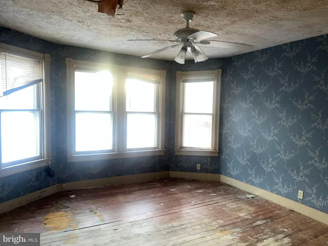 an empty room with a window and a chandelier fan