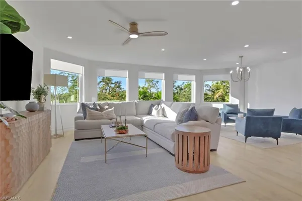 a living room with furniture a flat screen tv and a large window
