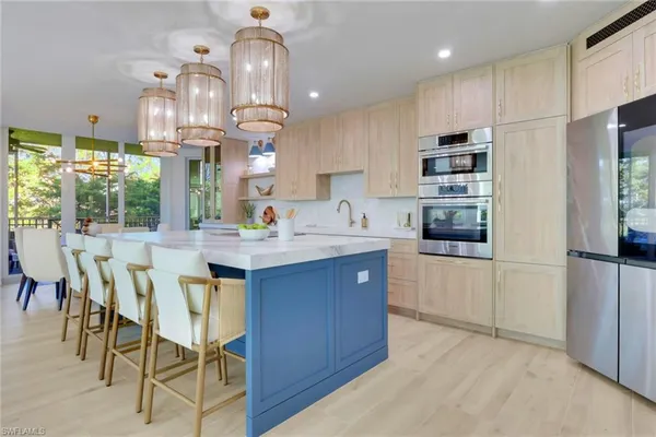 a kitchen with stainless steel appliances kitchen island granite countertop a table chairs sink and cabinets
