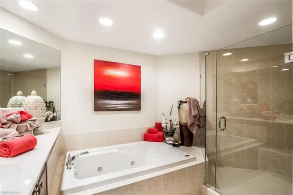 a bathroom with a tub sink mirror and shower